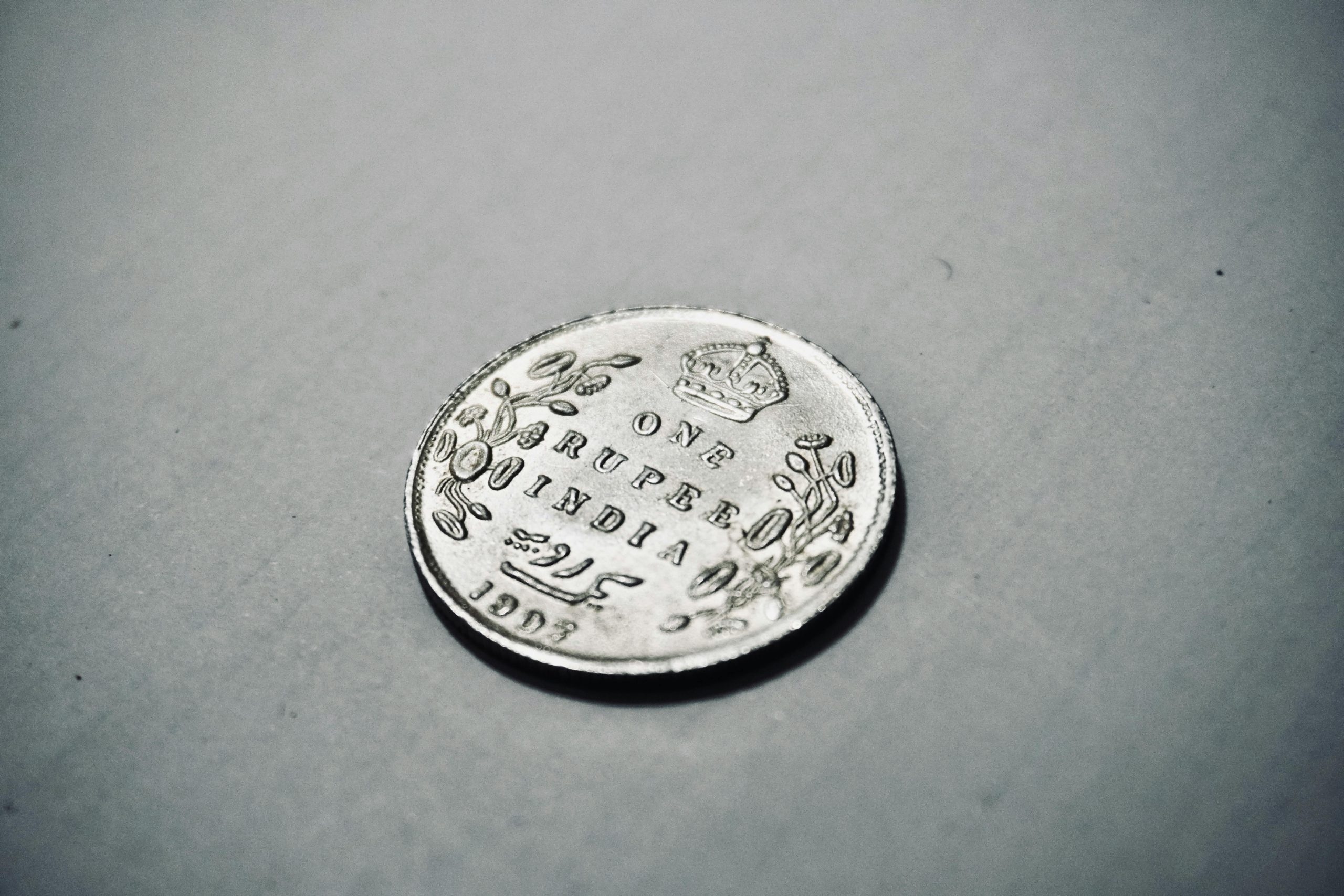Close-up photograph of a 1907 silver Indian rupee coin with intricate details.